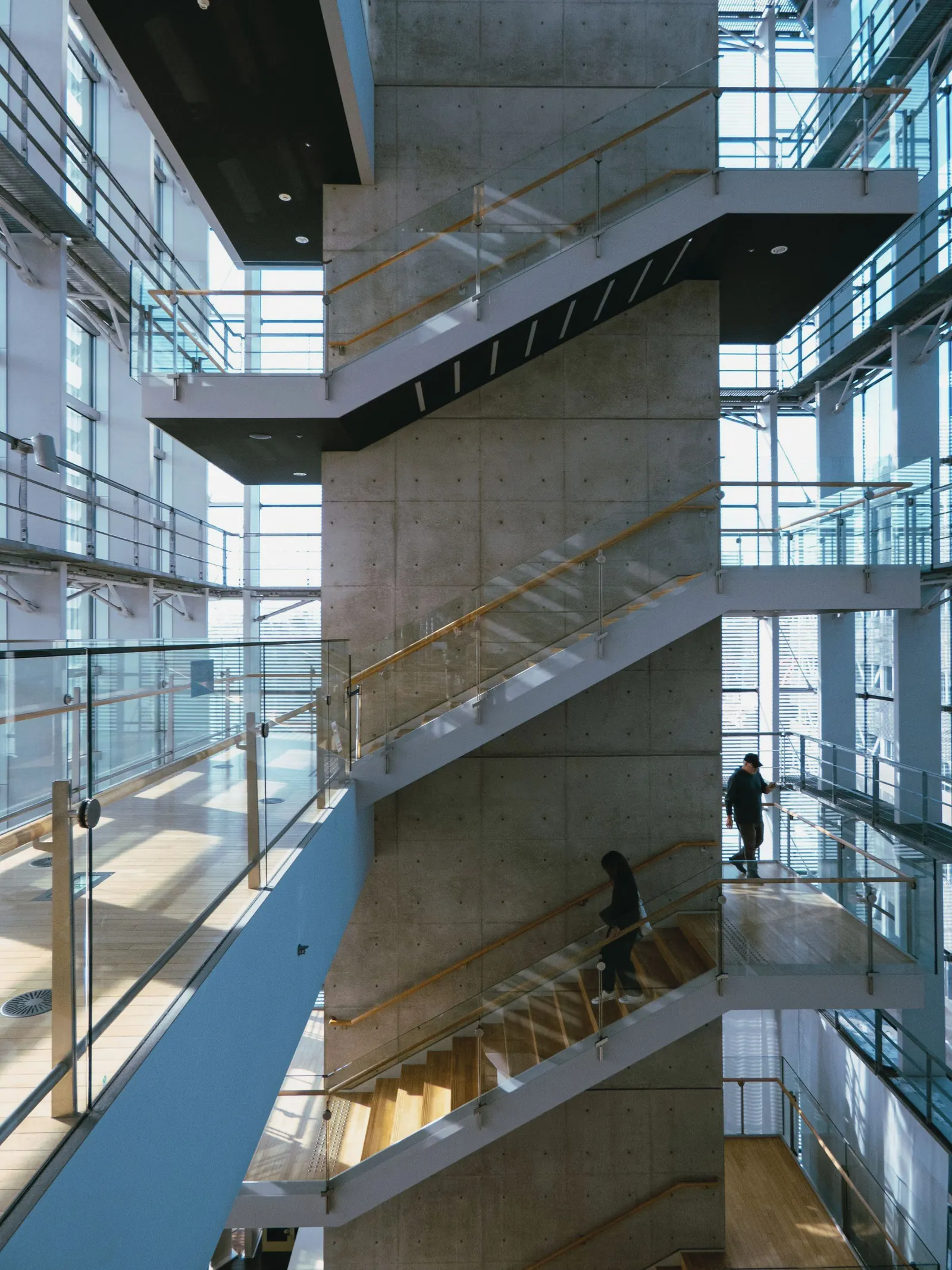 Open staircases zigzag up a concrete and glass atrium filled with daylight.