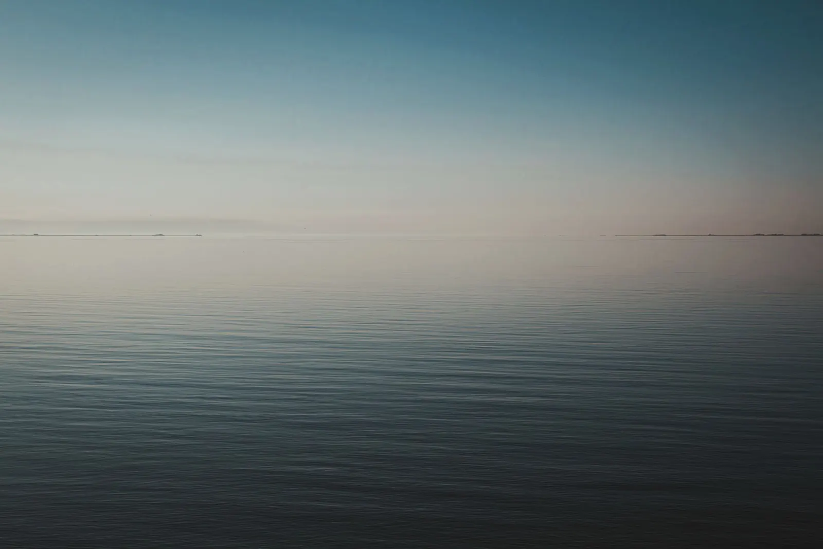 Perfectly calm open water meeting a soft horizon at first light.