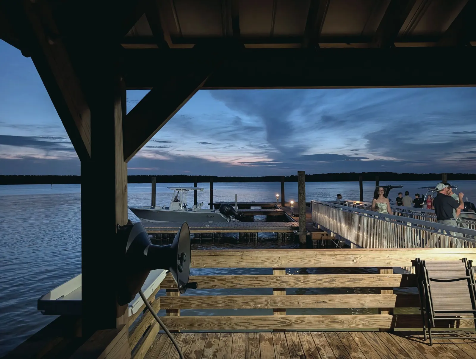 A covered wooden dock on the Mount Pleasant waterfront looking out over the harbor at dusk.