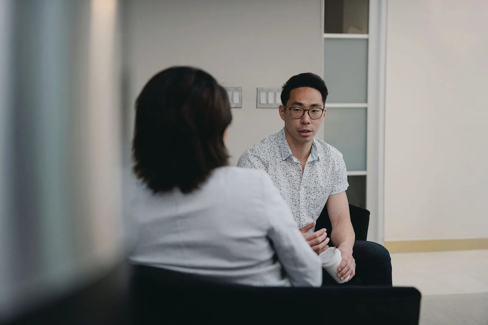 Two colleagues sit facing each other in a quiet office, deep in conversation.